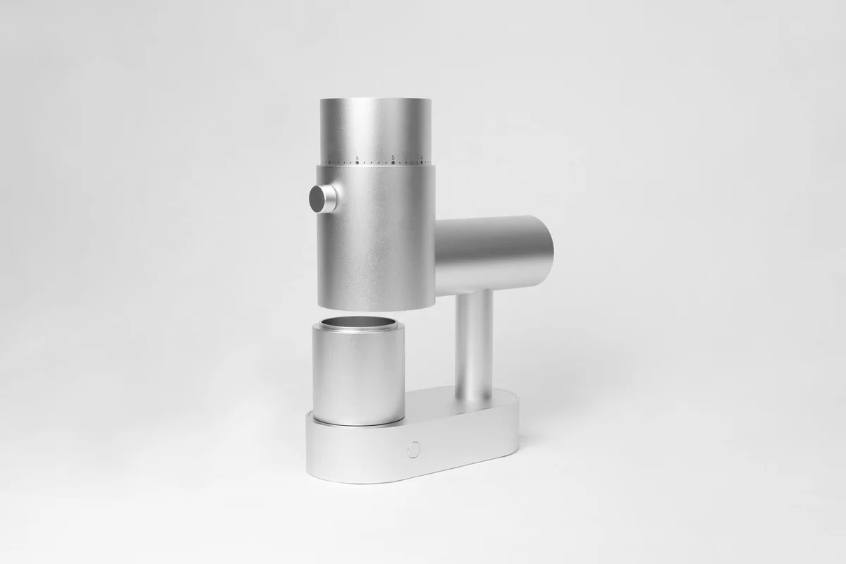 Silver Option-O Lagom Casa grinder viewed at an angle with its matching dosing cup