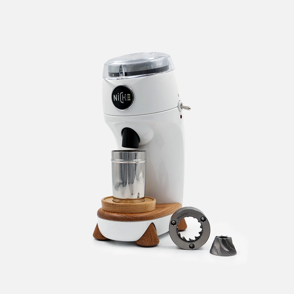 White Niche Zero grinder with oak trim and a steel dosing cup, with its conical burrs alongside